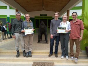 Gorilla trekking visitors holding trekking certificates outside a visitor information centre in Uganda.